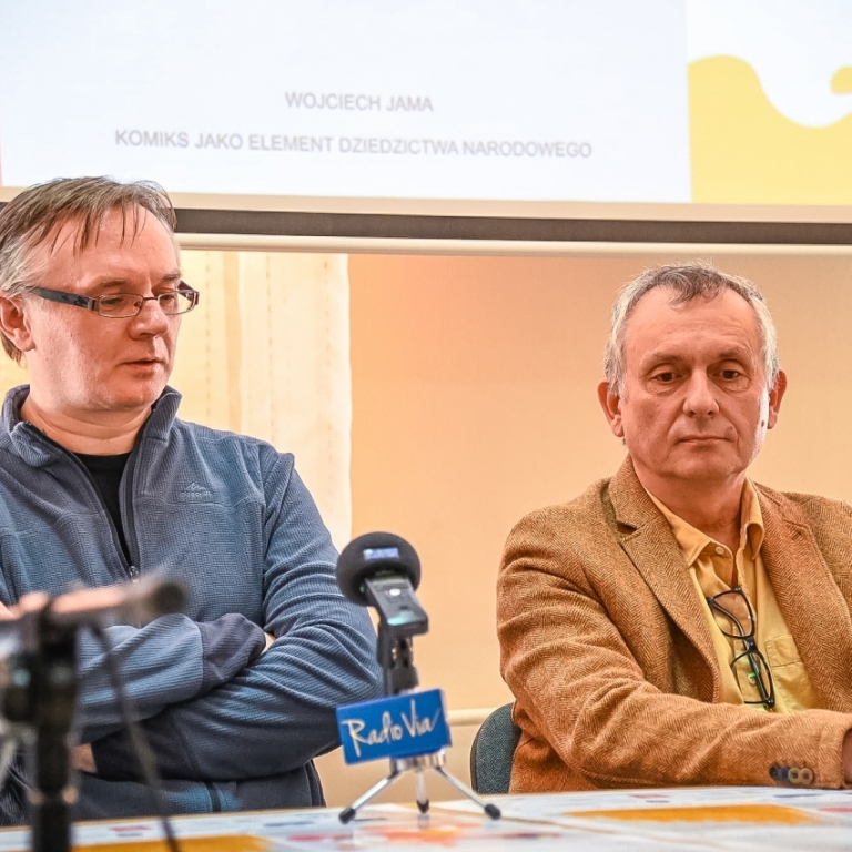 Wojciech Jama i Maciej Mazur siedzą przy stole w trakcie konferencji na stole stoją mikrofony