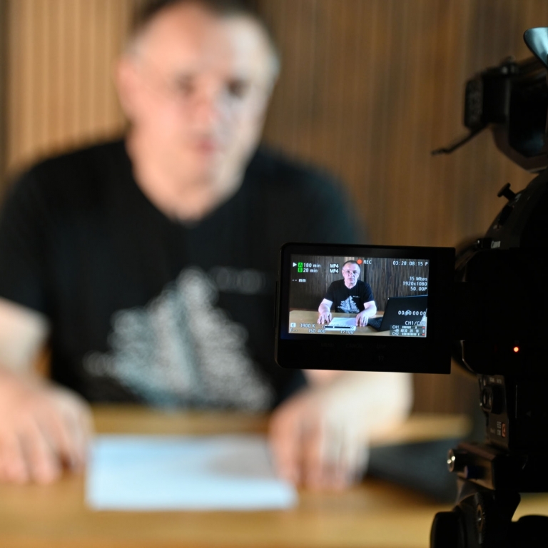 Artystyczne zdjęcie w czasie wykłądu zdjęcie wyświetlacza kamery na którym widać Wojciecha Birka podczas wykładu