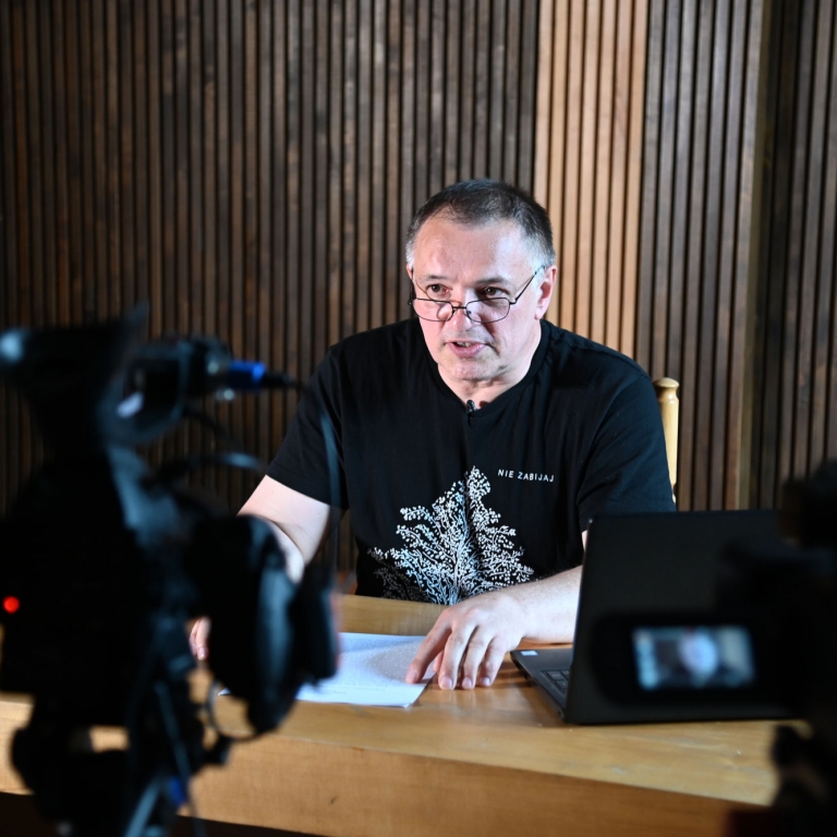 Wojciech BIrek podczas wykładu w tle widać dwie kamery, które nagrywają wykład