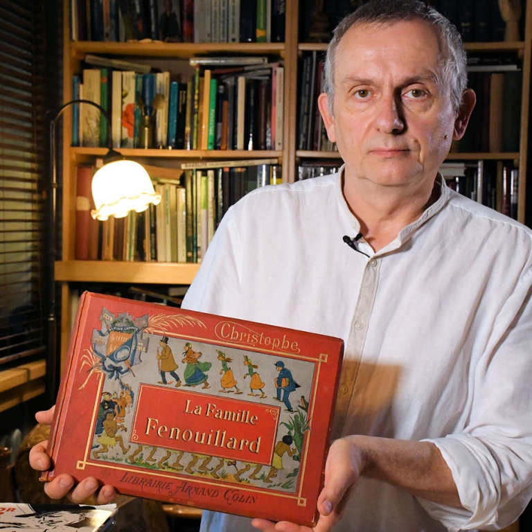 Wojciech Jama trzyma w ręku francuski komiks w czerwonej twardej okładce